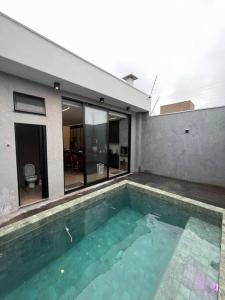 - une piscine en face d'une maison dans l'établissement Casa com piscina e área gourmet com churrasqueira integrada, à Maringá