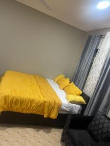 um quarto com uma cama com cobertores e almofadas amarelos em MED COZY FLAT GH em Acra