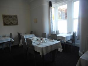 un restaurante con mesas y sillas blancas y una ventana en The George B&B en Weymouth