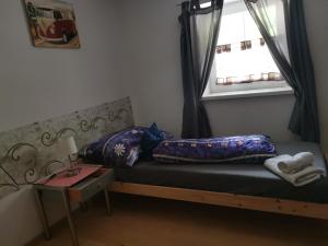 Habitación pequeña con cama y ventana en Pension Nachtviole, en Hüttau