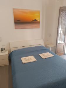 a bedroom with a blue bed with two towels on it at La Casetta di Elia in Lipari