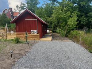 um celeiro vermelho com um caminho que leva a uma casa em Tinyhouse Tutviksvägen 35B em Vendelsö