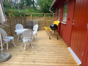 eine Terrasse mit Stühlen, einem Tisch und einem Grill in der Unterkunft Tinyhouse Tutviksvägen 35B in Vendelsö