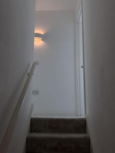 a staircase with a light on the wall and a light on the ceiling at Stylish & Cosy Nest near River Thames in London