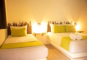 a bedroom with two beds with yellow and white at Hotelito El Cuyo in El Cuyo