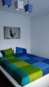 a bedroom with a colorful bed with a painting on the wall at Cantabria, amplio piso .Se admiten mascotas in Bádames