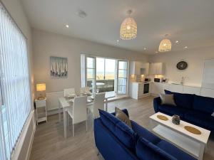 a living room with a blue couch and a table at Beachfront Bliss Apartment - Near Hythe - On Beach Seafront - Private Parking in Dymchurch