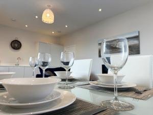 a dining room table with wine glasses on it at Beachfront Bliss Apartment - Near Hythe - On Beach Seafront - Private Parking in Dymchurch