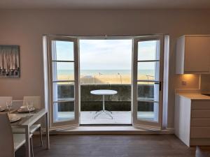 a kitchen with a sliding glass door with a view of the beach at Beachfront Bliss Apartment - Near Hythe - On Beach Seafront - Private Parking in Dymchurch