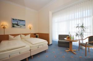 奧茨巴德賓茲的住宿－賓澤霍夫酒店，一间卧室配有一张床、一把椅子和一张桌子