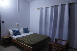 um quarto com uma cama com uma cortina e uma cadeira em Au cœur de Ouidah em Ouidah