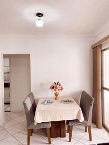 una mesa de comedor con un jarrón de flores. en APTO - Espaço Village Completo - 2Q en Vitória