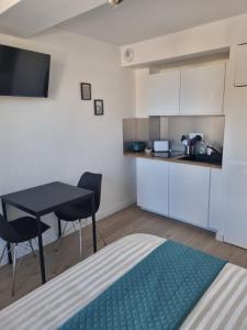 a small kitchen with a table and chairs in a room at MUTUM - Studios 2 personnes, idéalement placés à 100m de la plage in Dieppe