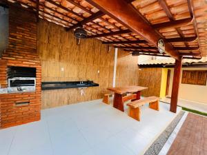 eine Küche mit Holzwänden, einem Tisch und Bänken in der Unterkunft Casa de Temporada - Praia Miaí de Baixo - Coruripe in Coruripe