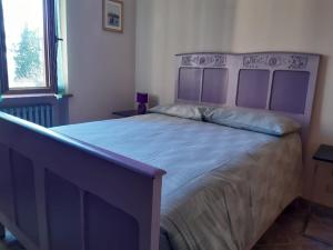 a bedroom with a large bed with a purple headboard at Villa Elma in Cigliè