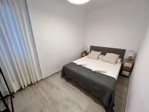 Schlafzimmer mit einem Bett mit weißer Bettwäsche und Kissen in der Unterkunft Apartamenticos La Paz I in Saragossa