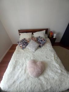 Una cama con una almohada en forma de corazón. en Les Jardins de l'Imaginaire en Monségur