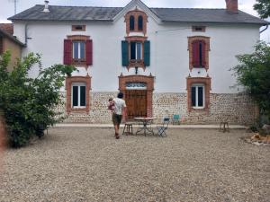 uma mulher a andar em frente a uma casa em Les Jardins de l'Imaginaire em Monségur