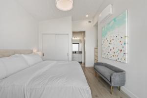 1 dormitorio blanco con 1 cama grande y 1 silla en Beachfront Luxury Suite #18 at THE BEACH HOUSE, en Campbell River