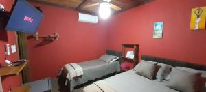 ein rotes Zimmer mit 2 Betten und einem Spiegel in der Unterkunft Chalés Guigó-Cumuruxatiba in Cumuruxatiba