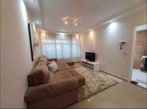 a living room with a brown couch and a television at Casa maravilhosa e completa, ótima localização in Sao Paulo