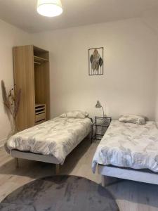 a bedroom with two beds and a lamp on the wall at Cosy Apartment In paris in Saint-Ouen