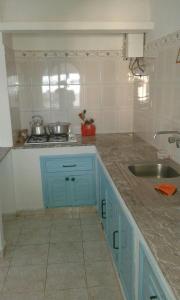 a kitchen with blue cabinets and a sink at Appart Hôtel La Planque in Oued Laou