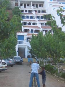 dos hombres en una bicicleta delante de un edificio en Appart Hôtel La Planque, en Oued Laou