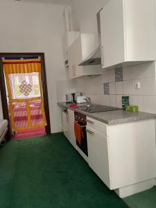 a kitchen with white cabinets and a green floor at Volkstheater Apartment. in Vienna