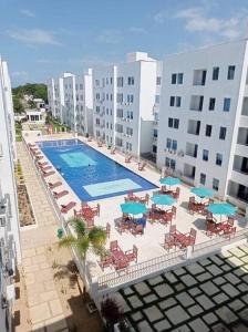 una vista aérea de una piscina con sillas y sombrillas en Cómodo Apartamento en zona Privada! cerca al Mar., en Coveñas