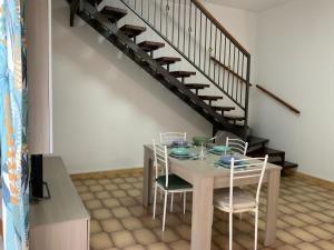 een eetkamer met een tafel en stoelen en een trap bij Al numero 5 in Francavilla di Sicilia