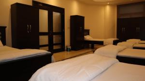 Habitación con 4 camas y sábanas blancas. en Budget Backpackers Hostel, en Abu Dabi