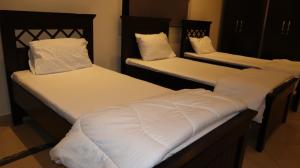Habitación con 2 camas individuales y sábanas blancas. en Budget Backpackers Hostel, en Abu Dabi