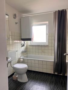 een badkamer met een toilet, een bad en een raam bij Gäste-, Handwerkerzimmer in Rosenfeld