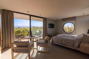 um quarto com uma cama, uma mesa e uma grande janela em Posada Mawida em Maipú