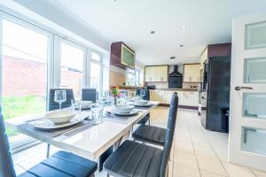 a kitchen with a table and chairs and a kitchen withwindows at Modern 4 Bed Hayes Home (Free Parking) in Hayes