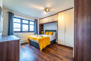 a bedroom with a bed with a yellow blanket on it at Modern 4 Bed Hayes Home (Free Parking) in Hayes