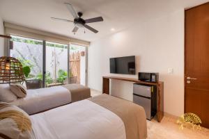 a bedroom with two beds and a flat screen tv at NHOA 108A Lux 2BR Condo Plunge Pool in Aldea Zama in Tulum