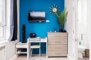 a room with a desk and a tv on a blue wall at Quality Spitalfields Accommodations in London
