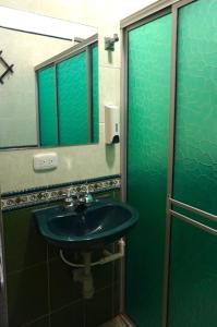 Baño verde con lavabo y espejo en Hostal Castañeda, en San José del Guaviare