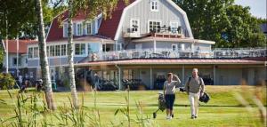 a man and woman walking in front of a large house at Grundéns Hotell in Grundsund