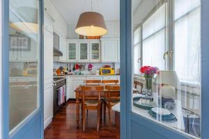 cocina con armarios blancos, mesa y sillas en Noisette Casa con giardino en Milán