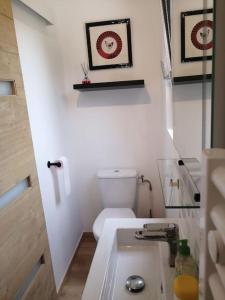 La salle de bains blanche est pourvue de toilettes et d'un lavabo. dans l'établissement Studio Les petites poules, à Saint-Lyphard