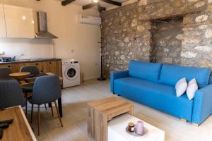 a living room with a blue couch and a kitchen at Lithic Suites 1 in Kalabaka