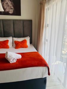 - une chambre avec un lit doté d'oreillers orange et une fenêtre dans l'établissement The blyde-Luxury one bedroom apartment, à Pretoria