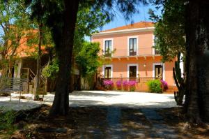 una casa rosa con árboles delante de ella en Villa Bonaccorso - antica e maestosa villa con piscina ai piedi dell'Etna, en Viagrande