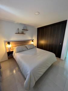 a bedroom with a large white bed with a wooden headboard at Apartamento en el sur de Cali, Barrio Tequendama in Cali