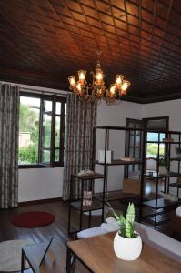 ein Wohnzimmer mit einem Kronleuchter, Tischen und Fenstern in der Unterkunft Timber Guest House in Berat