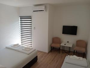 Zimmer mit 2 Betten, einem TV und einem Tisch in der Unterkunft Vinarija "Đelmo" apartments in Trebinje