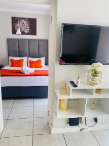a bedroom with a bed with orange pillows and a tv at The blyde-Luxury one bedroom apartment in Pretoria